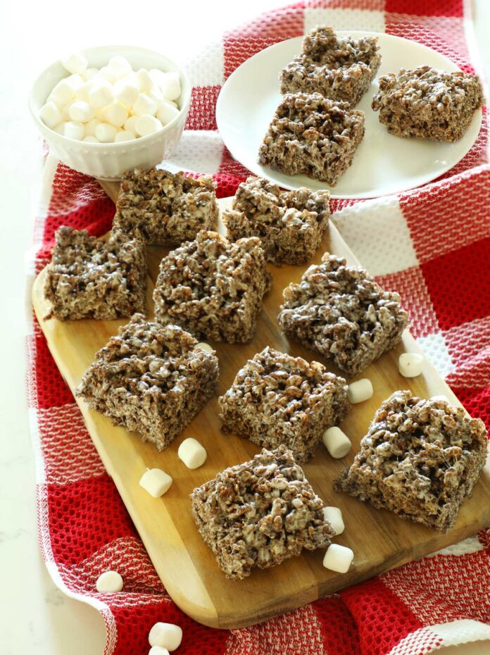 Chocolate Rice Krispie Treats squares on a cutting board on a kitchen counter with mini marshmallows.